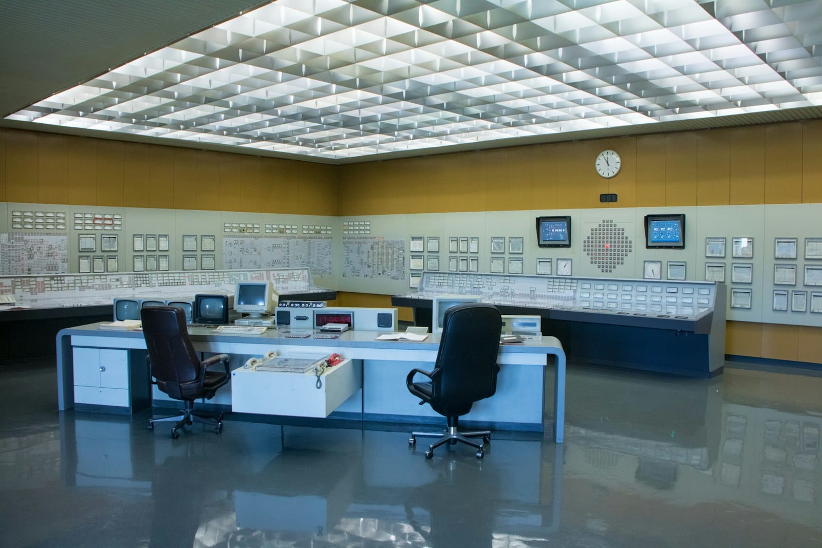 A dark control desk of monitors, representing continuous monitoring and early-signal detection.