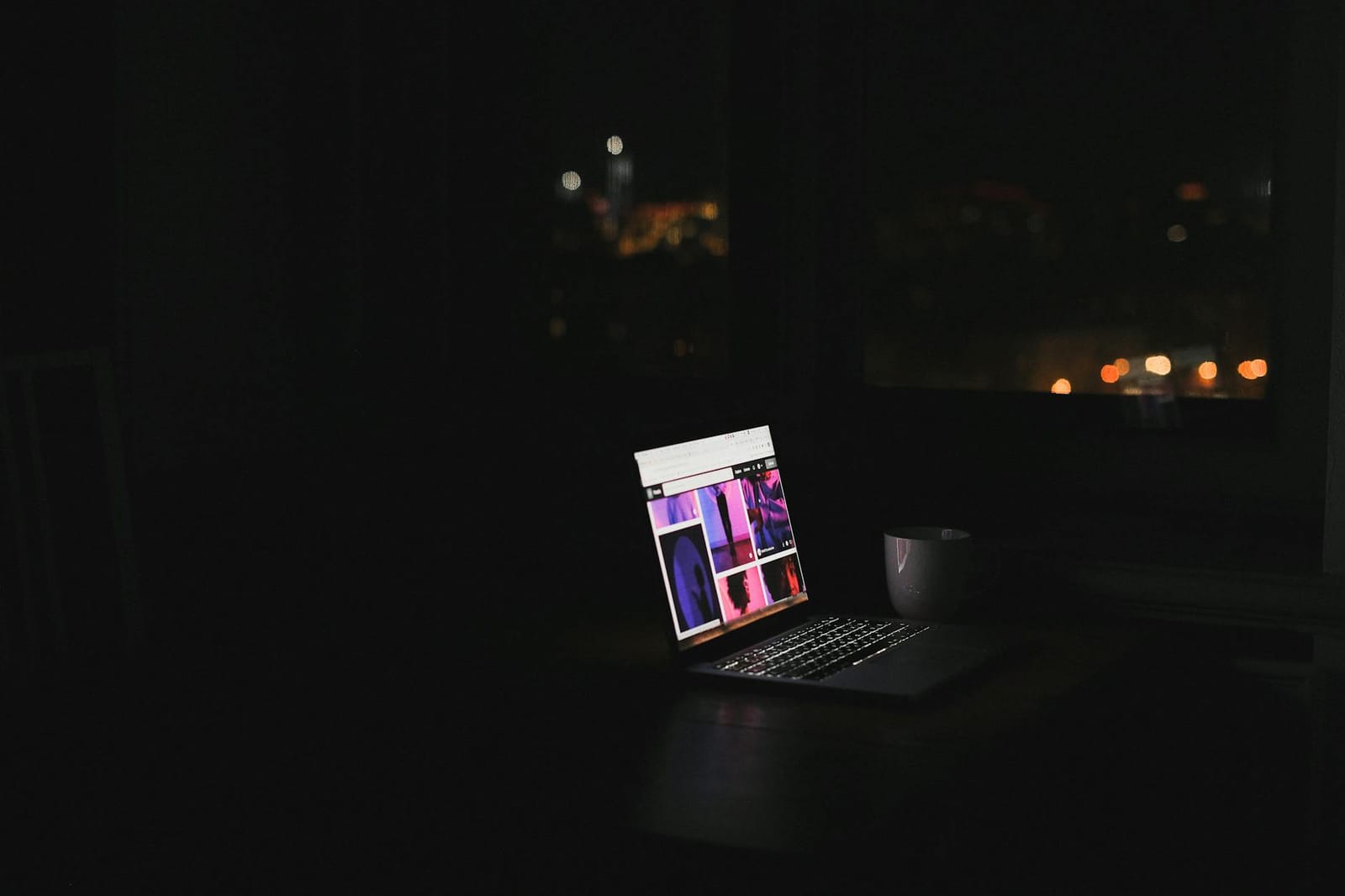 A laptop glowing in a dark room at night.